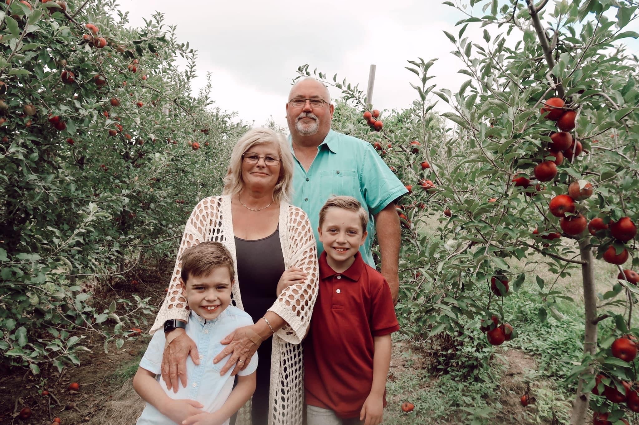 A family standing together in the apple rows at Historic Weston Orchard