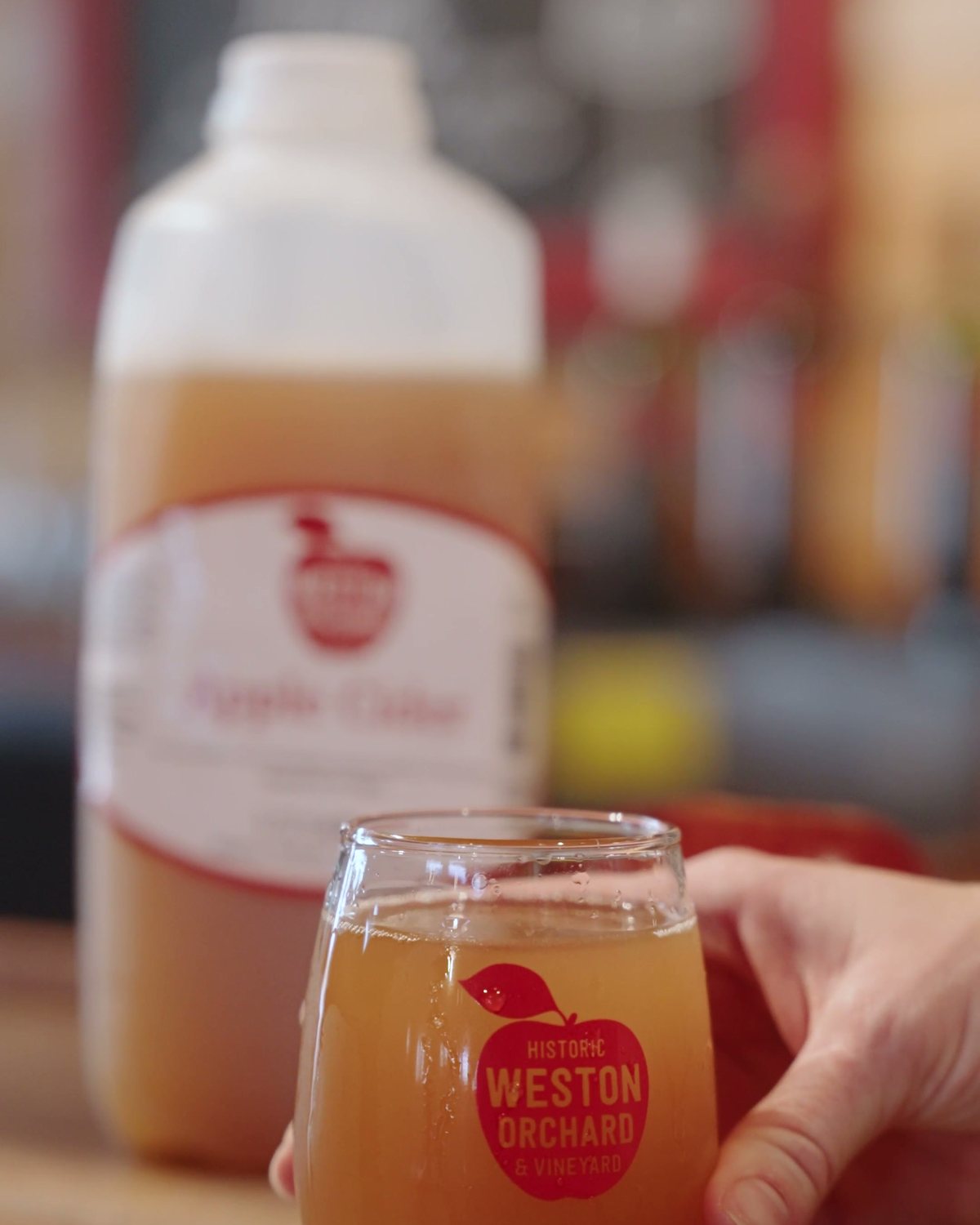 A glass of fresh apple cider with the Historic Weston Orchard logo
